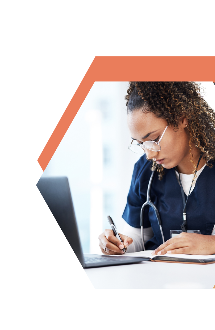 A healthcare worker in scrubs with a stethoscope writes in a notebook while looking at a laptop. The image, cropped in a hexagonal frame with an orange border on a white background, highlights care provided in Southwest Minnesota.